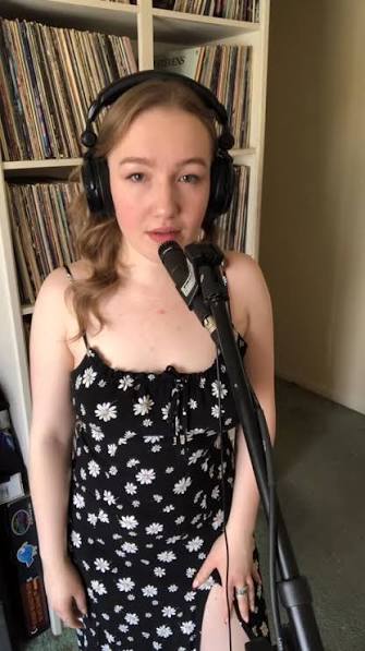 Coco singing into a microphone wearing headphones