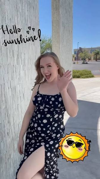 Coco waving outdoors in a floral dress